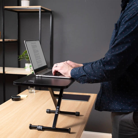 Black 28 Inch Standing Desk Converter Sit To Stand Monitor Riser With Scissor Lift Height Adjustment in a home office setup