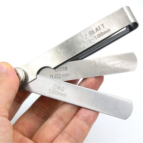 Stainless steel 32-piece feeler gauge with SAE/metric blades, offset valve thickness gauge, held in hand.