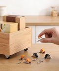 Person holding an orange 8 Pack Rock Solid Slick Low Profile Fixed Caster Wheel above wooden box with storage bins.