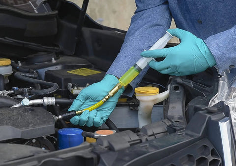 LEAKFINDER LF021 auto refrigerant leak detector kit; blue-gloved technician injects yellow dye into car AC hose