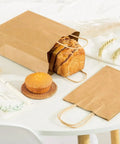 Bulk Kraft Paper Bags With Handles 50 Pieces 26x12x31 Cm Takeout Coffee Grocery Shopping Bags shown with bread and muffin
