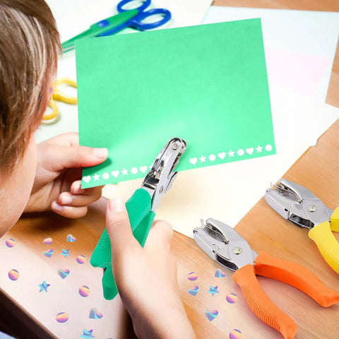 Child using Three Piece Hole Punch Set With Round Heart And Star Shapes For One Quarter Inch And Three Sixteenth Inch Holes on green paper