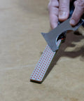 Person using Dia Fold Handy Portable Pocket Diamond Sharpener Double Sided With Extra Fine And Fine Grits on a table.