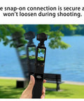 Hand holding High Capacity Battery Handle For Osmo Pocket 3 and 4 On The Go 5000mAh Power Grip with Mini Tripod by a lake