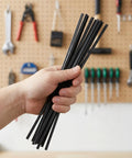 Person holding a bundle of black PP rods from the 100 Pc Set for car bumper repairs using heat tools.