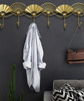 Heavy Duty Artisan Quality Golden Fan Shaped Wall Mount Coat Hook with shirt and bag on hooks in stylish entryway.