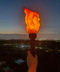 Handheld Realistic Flameless LED Torch Light Prop Lamp For Parties, Holidays, overlooking cityscape at night, flame effect visible.