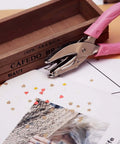 1mm Circle Hole Punch For Craft Paper With Pink Handy Grip Handle next to cut-out craft paper and decorative box