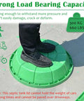 Person standing on green manhole cover demonstrating strong load bearing capacity of 20 Inch Lawn Manhole Cover Set 4 Piece Resin Concealed Inspection Covers For Parks Gardens And Residential Areas Durable Outdoor Drainage Solution Ideal For Lawn And Gardens Installations.