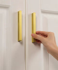Hand holding 2 Pack Solid Brass Cabinet Handles In Brushed Gold Finish Modern Kitchen Hardware With Three And Three Quarters Inch Hole Center