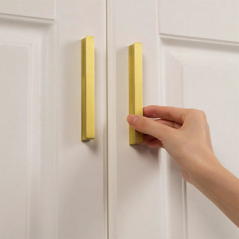 Hand holding 2 Pack Solid Brass Cabinet Handles In Brushed Gold Finish Modern Kitchen Hardware With Three And Three Quarters Inch Hole Center