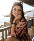 Pretty Sweet Slim Leather Band Compatible With Apple Watch For Women, worn by a smiling woman on a beachside patio.