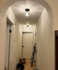 Hallway with matte black flush mount ceiling light, clear glass shade, brass accent canopy, modern vintage style.