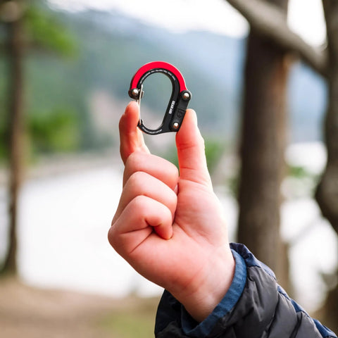 Person holding HeroClip Mini Carabiner Clip And Hook 2 Pack For Travel Luggage Purses And Small Bags Stealth Black 3 In 1 Clip