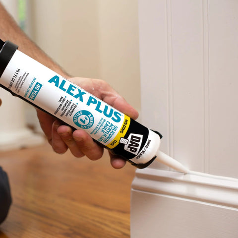 Person applying Paintable Siliconized Acrylic Caulk for Multi Surface Sealing and Waterproofing to baseboard joint