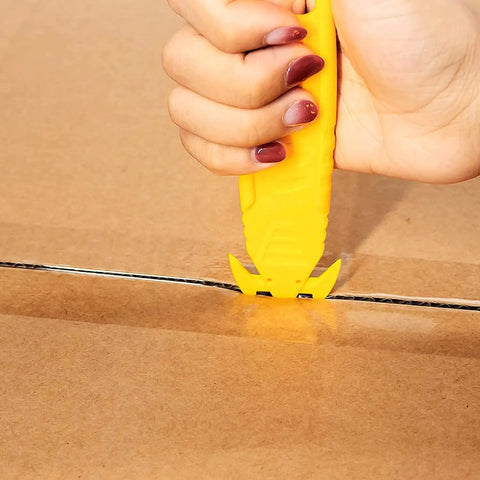 Hand using 50 Pack Safety Box Cutter With Double Sided Concealed Blade Stainless Steel Package Opener for slicing cardboard