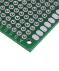 Close-up of a green double-sided PCB from Pack Of 12 Double Sided PCB Prototyping Boards For Diy Soldering Breadboard Projects, 4cm by 6cm Universal Printed Circuit Boards In Red Green And Blue, Perfect For Prototyping And Custom Electronics