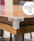 Close-up of a clear soft PVC edge protector on a wooden table corner, part of the 10 Pack Table Corner Guards For Kids And Pets.