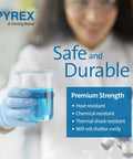 Close-up of a gloved hand holding a Pyrex beaker filled with blue liquid, highlighting safety and durability features.