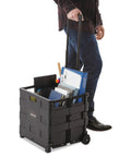 Person pulling a Collapsible Rolling Storage Crate With Telescoping Handle, 1.7 Cu Ft Capacity, filled with office supplies.