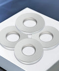 Top view of four silver stainless steel flat washers with 1/4 inch inner holes for bolts