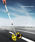 Cloimei Double Wheel Measuring Wheel Ergonomic Distance Wheel 9999m Precision Measurement Tool on road with yellow wheels.