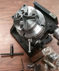 Heavy Duty Eight Inch Precision Tilting Rotary Table With No Fuss Zero To Ninety Degree Tilt Capability And Four Jaw Self Centering Chuck Setup For Dead Straight Mill Projects on a wood surface with tools.