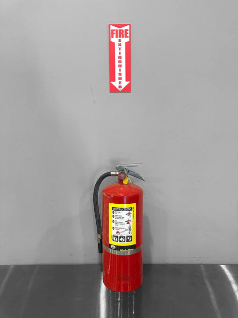 Wall-mounted fire extinguisher with "Fire Extinguisher" sign above, demonstrating Four Pack Fire Extinguisher Signs For Office And Warehouse Safety, Durable 80 Mil Thick Plastic, OSHA Compliant, Easy To See 12 Inch Tall 4 Inch Wide, Ideal Safety Signage For Businesses.