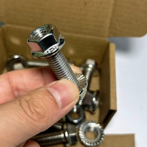 Close-up of a hand holding a 304 Stainless Steel Flange Hex Head Bolt for exhaust manifold kit M10 1.5 pitch 35mm, with nuts in box