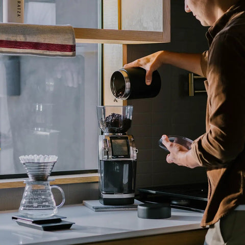 Heavy Duty Commercial Coffee Grinder Featuring Flat Steel Burrs And 260 Grind Settings For Espresso And Pour Over Brewing with coffee beans being poured.