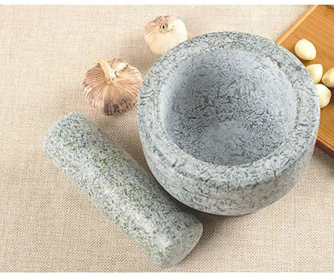 Heavy Duty Granite Mortar And Pestle Set With Anti Slip Base For Grinding Spices Herbs Garlic Pepper Nuts Coffee Beans And More Pro Grade Guacamole And Salad Prep Non Porous Easy To Clean And Durable Kitchen Tool on a kitchen counter with garlic cloves