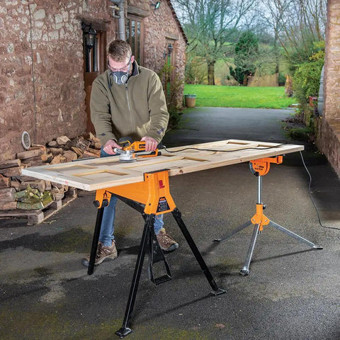 Person using Beefed Up Heavy Duty Portable Clamping Jawhorse With Foot Pedal For Hands Free Operation Folding Workbench Tripod Table 2200lb Capacity Ideal For Woodworking Repairs And Construction outdoors.