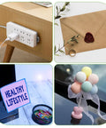 Power strip on wooden table, wax-sealed envelope, healthy lifestyle sign, and pastel balloon decor on reflective surface.