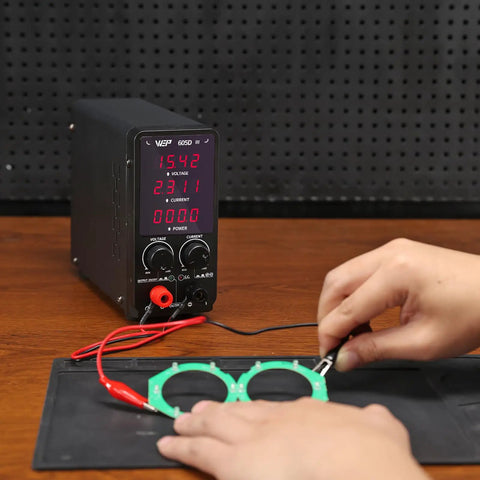 Beefy 60V 5A Adjustable DC Bench Power Supply With Crisp Readouts and Alligator Clips used for electronics testing on table.