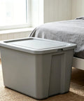 Straight Up Tough As Nails Heavy Duty Plastic Storage Bin With Secure Snap On Lid For Real Garage Setup Or Home Decluttering Projects Gray 18 Gallon Capacity next to bed in a bedroom.