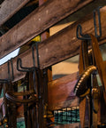 Two Pack 4 Inch Heavy Duty Tack Hooks Over Rail Bridle Rack holding horse bridles on a wooden stall wall, black metal hooks