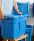 Person carrying a Heavy Duty Stackable Storage Bin 18 Gallon Plastic Tote With Lids And Handles Heritage Blue.