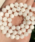 Legit Premium Natural White Pearl Shell Beads For Diy Jewelry Making With Awesome Iridescent Glow And Smooth Round Edges in a hand.