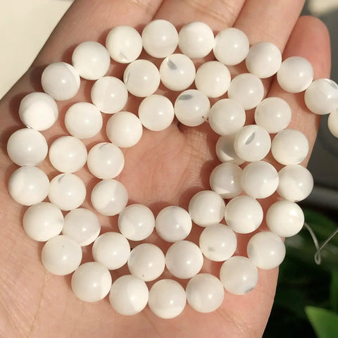 Legit Premium Natural White Pearl Shell Beads For Diy Jewelry Making With Awesome Iridescent Glow And Smooth Round Edges in a hand.
