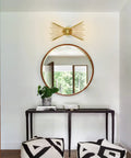 Antique Brass Two Light Modern Mid Century Wall Sconce in a stylish living room with a round mirror and black console table.