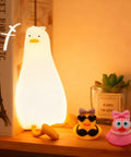 Squishy Silicone Rubber Duck Night Light For Nursery Baby And Kids Dimmable Rechargeable Touch Led Lamp BPA Free Non Toxic Bedside Light For Breastfeeding Shatterproof Safe Cozy Glow on a bookshelf