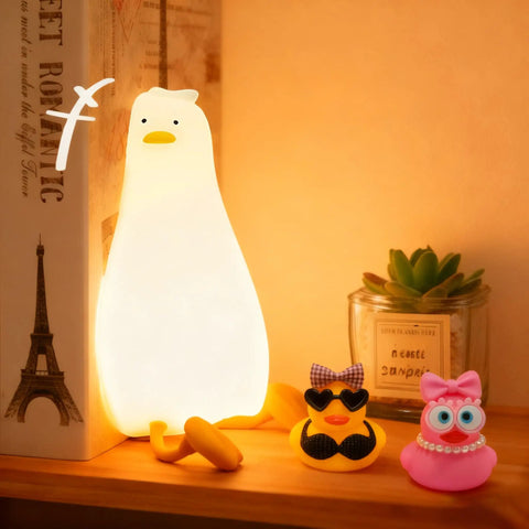 Squishy Silicone Rubber Duck Night Light For Nursery Baby And Kids Dimmable Rechargeable Touch Led Lamp BPA Free Non Toxic Bedside Light For Breastfeeding Shatterproof Safe Cozy Glow on a bookshelf