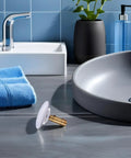 Copper Pop up Bathtub Plug with Bounce Design for Drain Hole beside a grey sink, featuring a brass connector and a blue towel.