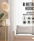 Freestanding Metal Coat Rack With 8 Hooks, Space Saving Hall Tree in gold next to a sofa holding a hat and bag.
