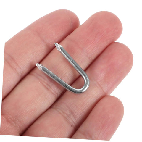 Close-up of a single U-shaped metal fence staple held in hand, part of a 50 Pack U Shaped Fence Staples For Quick Install And Strong Hold Durable Metal Garden Stakes For Fences Landscaping And DIY Projects Multi Function Iron Pegs.