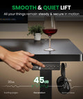 Electric Standing Desk 60x28 Inch Sit Stand Desk With 1 Inch Thick Top being adjusted with wine glass and plant on top.
