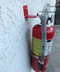 Side view of Heavy Duty Fire Extinguisher Bracket With L Hook Mounts, Wall Hanger, installed on a white wall holding red extinguisher