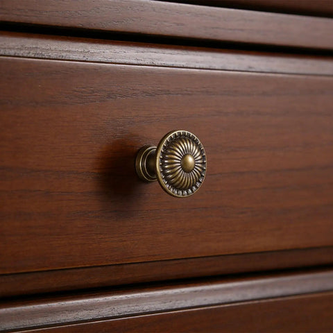 Antique patterned hardware knob on wooden dresser, illustrating Ten Pack One And One Quarter Inch Glossy Black Zinc Euro Style Cabinet Knobs