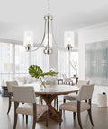 Three-Light Brushed Nickel Chandelier With Clear Glass Shades hanging over a round wooden dining table in modern home setting