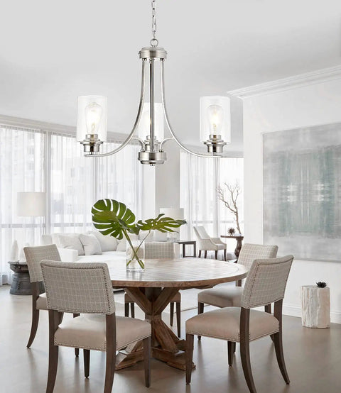 Three-Light Brushed Nickel Chandelier With Clear Glass Shades hanging over a round wooden dining table in modern home setting